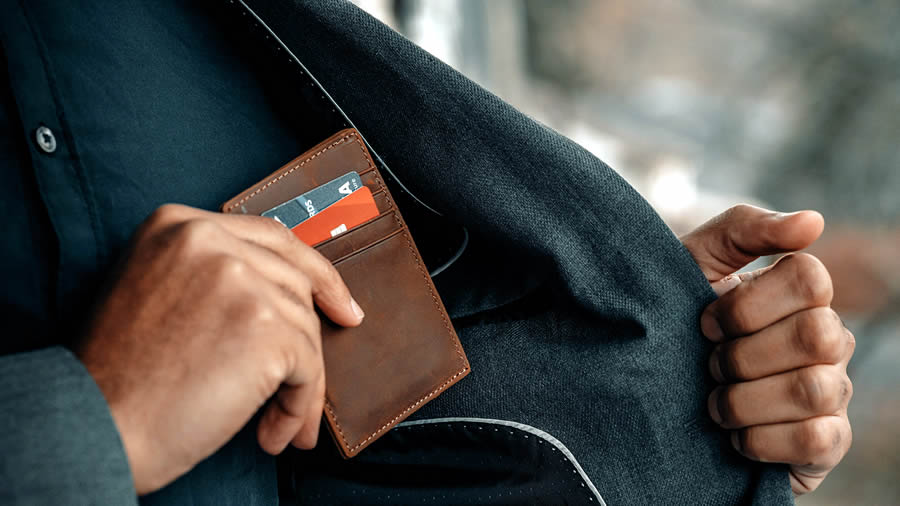 Una persona guardando una cartera con tarjetas bancarias en un bolsillo interior de su chaqueta.