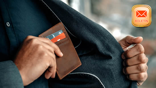 Una persona guardando una cartera con tarjetas bancarias en un bolsillo interior de su chaqueta.